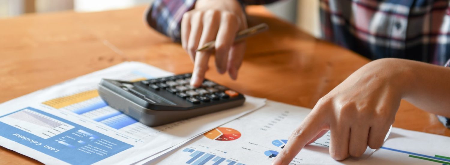 Hand pointer at graph and other hand hold pen and presses the ca Hand pointer at graph and other hand hold pen and presses the calculator.