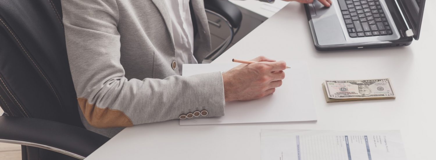 A male accountant works at a pc in an office at home. A male accountant works at a pc in an office at home. Payroll and cash withdrawal